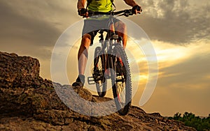 Enduro Cyclist Riding the Mountain Bike on Rocky Trail at Sunset. Close-up of Bicycle. Active Lifestyle Concept.