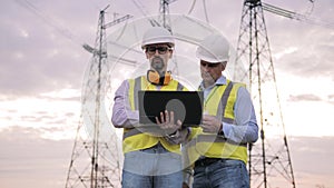 Enenrgy engineers inspecting a power line. Energetics specialists are having a discussion outdoors