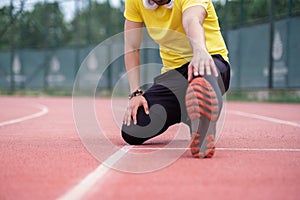 Energetic athlete in activewear and headphones warms up on running track at a city sports ground