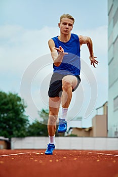 Energetic athlete dashing with determination. Full length portrait of professional sportsman fast running on sport field