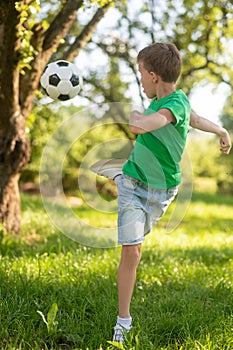 Energetic boy kicking soccer ball back.