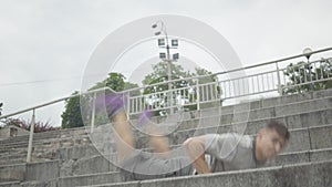 Energetic break dance of confident young Caucasian man on urban stairs. Portrait of handsome athletic guy dancing with