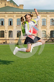 Energetic child in formal uniform with study books backpack jump in schoolyard happy celebrating, back to school