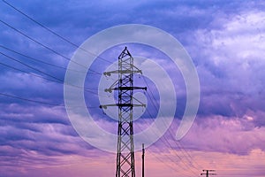 Energetic crisis situation conceptual image, silhouette of electricity pylons and power line cables against dramatic purple sunset