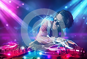 Energetic Dj mixing music with powerful light effects