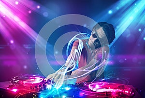 Energetic Dj mixing music with powerful light effects