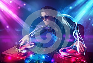 Energetic Dj mixing music with powerful light effects