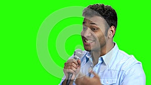 Energetic entertainer talking into microphone on green screen.