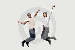 Energetic euphoric african american couple friends jumping with raised hands.