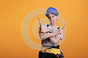 Energetic female construction worker holding screwdrivers