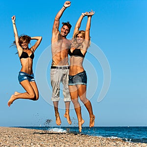 Energetic friends jumping on beach.