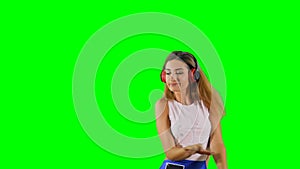 Energetic girl listens music in headphones at green background