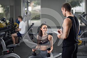 Energetic girl and man in black talking in gym.