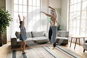 Energetic grandmother dancing in living room with granddaughter