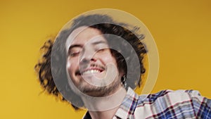 Energetic happy man dancing, yellow background. Smiling hipster guy portrait.