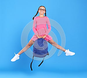 Energetic happy schoolgirl in eyewear with funny surprised facial expression jumping up in air