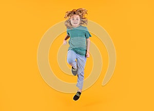 Energetic kid boy jumping and raising hands up on isolated studio background. Full length body size photo of jumping