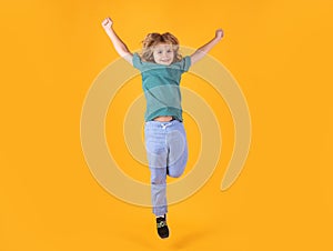 Energetic kid boy jumping and raising hands up on isolated studio background. Full length body size photo of jumping