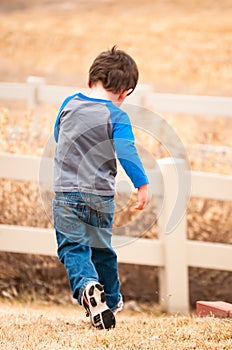 Energetic little boy running as he plays in the back yard