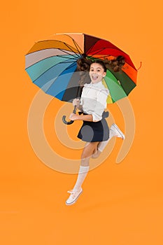 Energetic look. Adorable girl jumping with autumn look on yellow background. Cute little schoolchild having glamour look