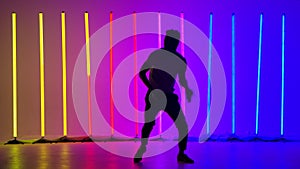 Energetic man dancing salsa in slow motion. The silhouette of a man practicing salsa steps in the studio against the