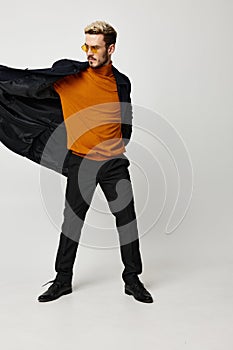 energetic man in an open coat and an orange sweater black pants model