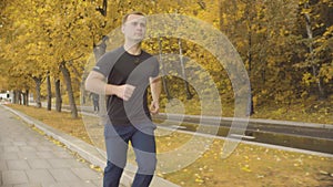 Energetic man in sportswear running along road in the park