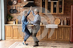 Energetic middle aged family couple dancing in kitchen.
