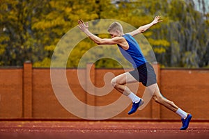 Energetic motion before an explosive jump. Side view full length portrait of professional sportsman fast running on