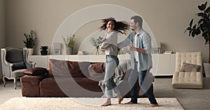 Energetic sincere young family couple dancing at home.