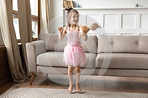 Energetic small child girl dancing alone in living room.