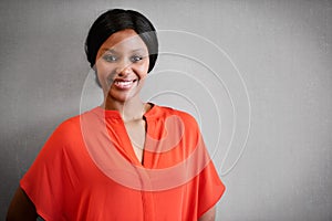 Energetic smile at camera by attractive black woman against grey