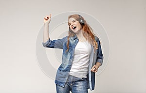 Energetic teen girl singing, listening to favorite music with headphones