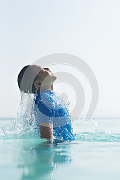 Energetic young boy jump out from a swimming pool