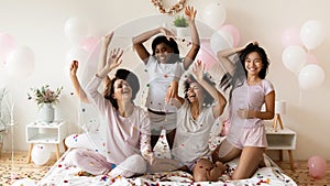 Energetic young diverse multiethnic girls playing with colorful confetti.