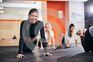 Energetic young lady performing push-ups in group workout