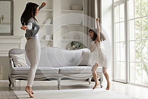 Energetic young mom dancing with happy little daughter