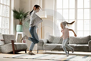 Energetic young mother dancing with small daughter at home.