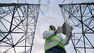 Energetics worker is standing between two power towers with a computer