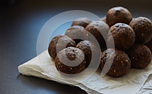 Energy balls on baked wax paper on a black background. Handmade raw vegan product. no bake