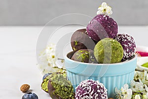 Energy balls and bites in chocolate glaze with flowers on white background . Healthy vegan snacks. Raw sweet dessert