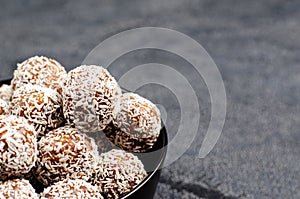 Energy balls from dates, peanuts, honey, oats in a black bowl on a dark background, copy space, flat lay