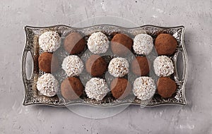 Energy balls of nuts and oatmeal with coconut and cocoa on a metal tray on a gray concrete background, horizontal format