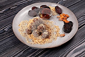 Energy balls on plate, sweets proper nutrition homemade. Made from dates, pine nuts, apricots, almonds and prunes, with honey.