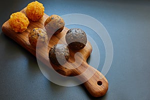 Energy balls on a wooden board on a black background with copy space