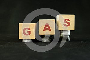 Energy crisis and high price of gas concept. Increasing stack of coins in wooden blocks with word gas on dark black background.