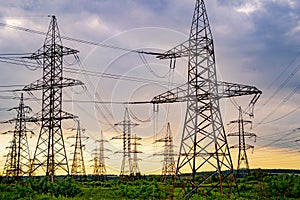 Energy distribution network. Electricity pylons against orange and yellow sunset. Selective focus.