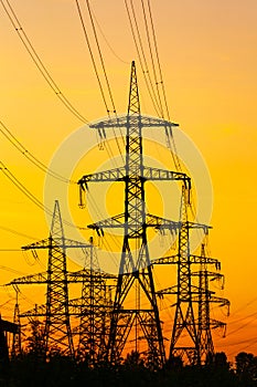 Energy Distribution Network - Electricity Pylons against Orange and Yellow Sunset. Selective focus.