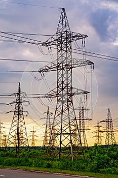 Energy distribution network. Electricity pylons against orange and yellow sunset. Selective focus.