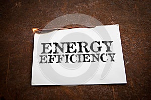ENERGY EFFICIENCY. Burning paper with text on a rusty metal background